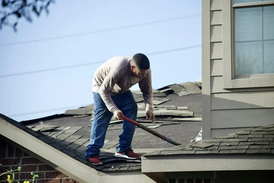 Roofer removing damaged shingles
